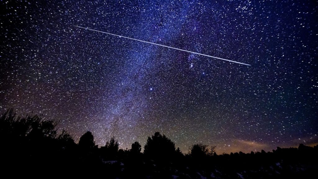 A photo of a shooting star in the starry night sky